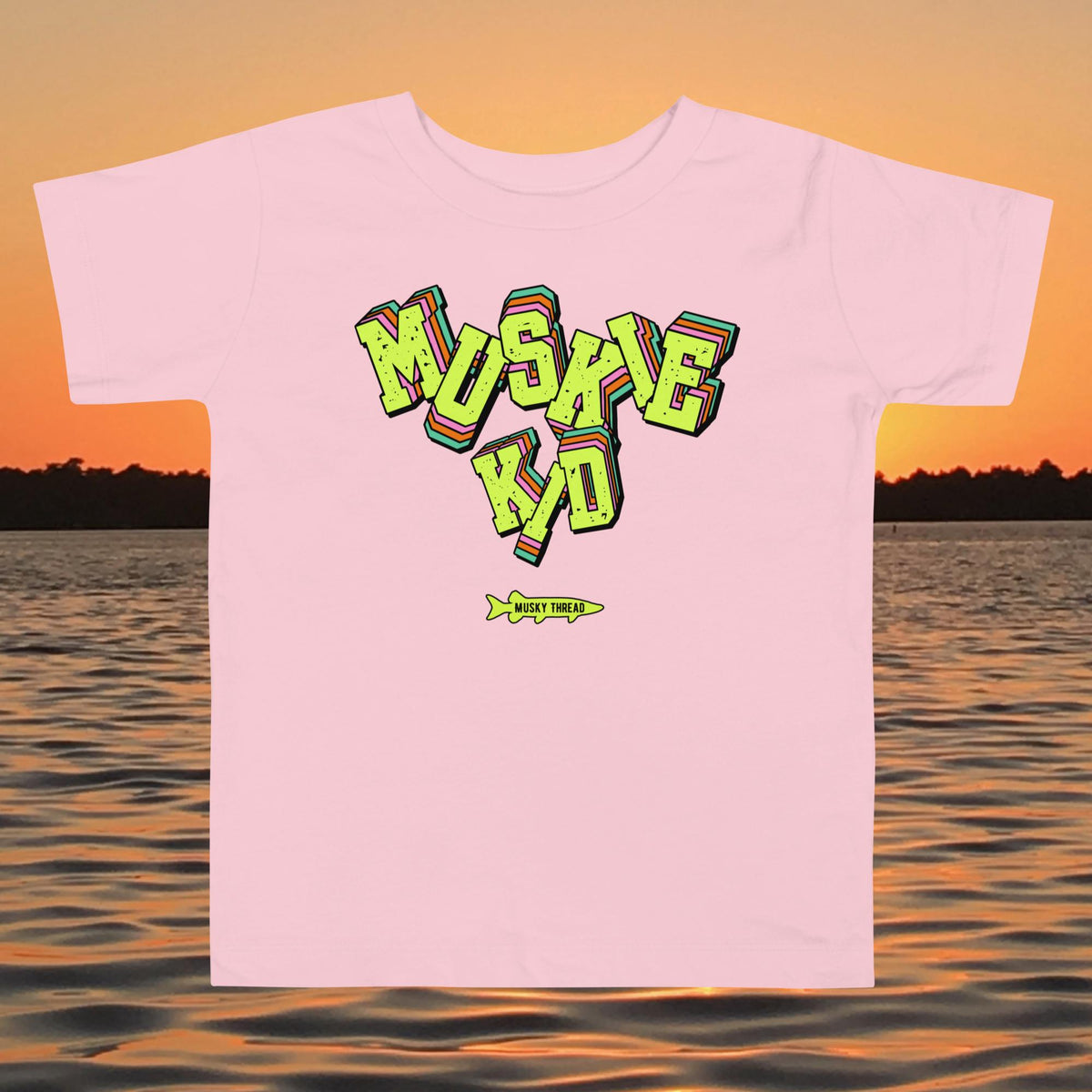 toddler t-shirt with neon green, pink, and teal "Muskie Kid" retro graphic and Musky Thread fish logo, shown against a lake sunset background