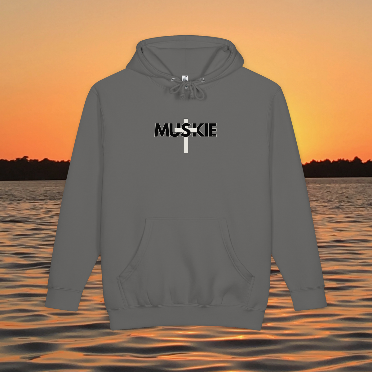 Minimalist Muskie Cross heavyweight pullover hoodie with black MUSKIE lettering crossed by a cream cross, shown over a sunset lake