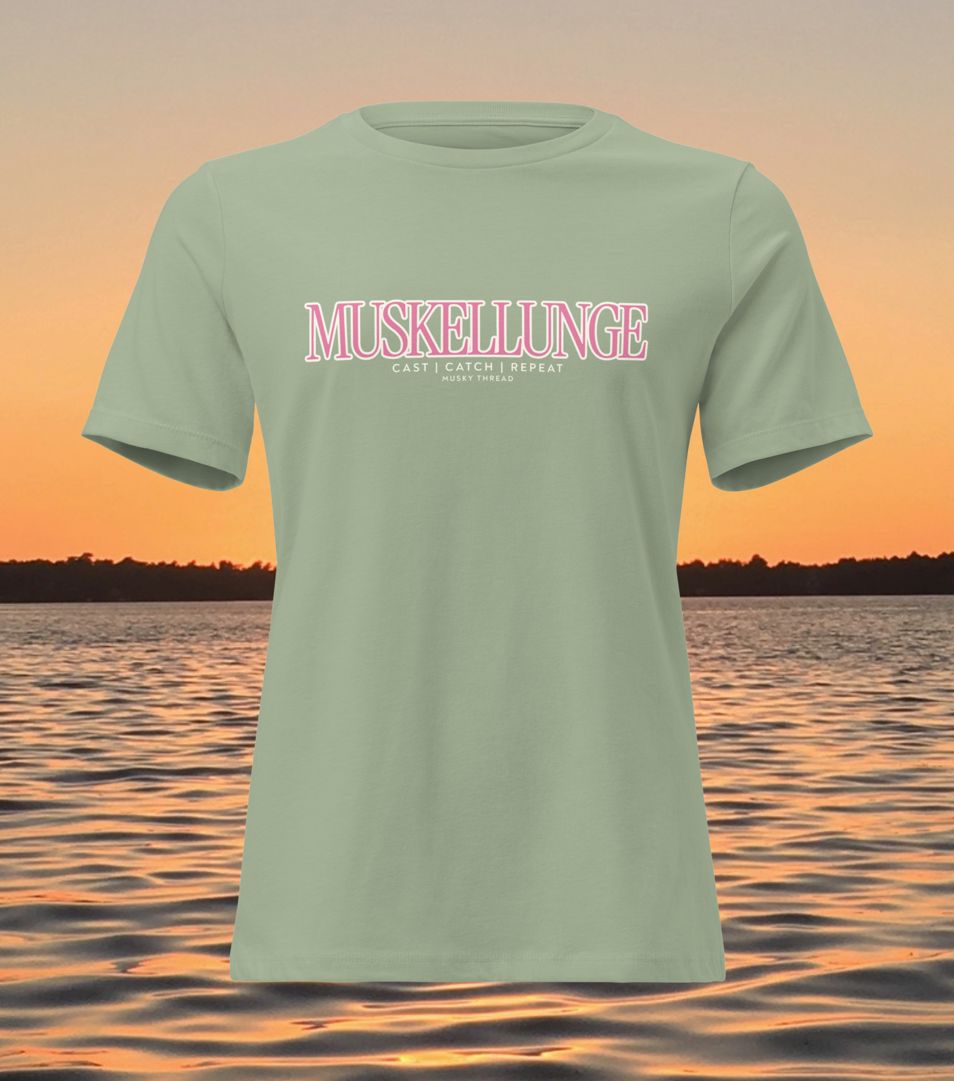 women's t-shirt with pink and white Muskellunge Cast Catch Repeat fishing design, lake sunset background
