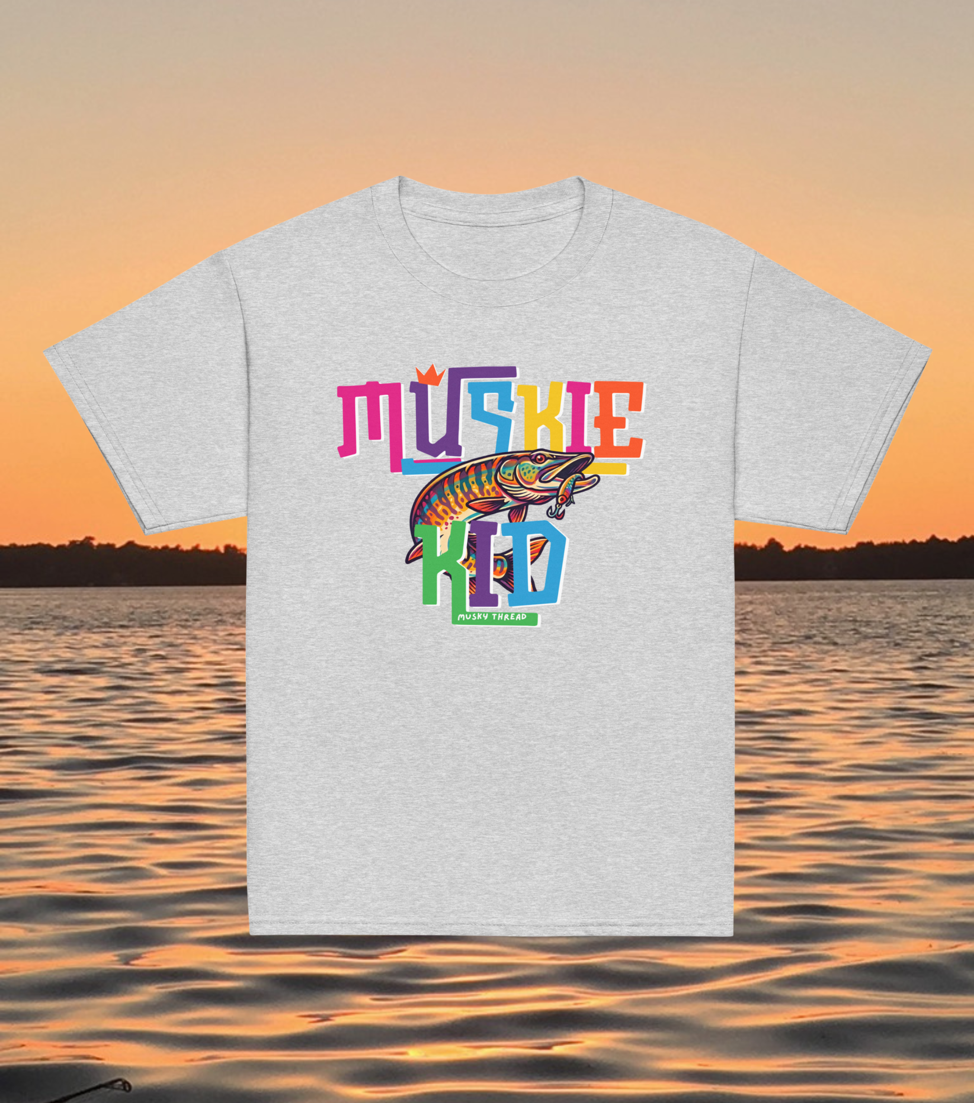 street-style youth graphic t-shirt with colorful hand-lettered Muskie Kid design featuring an illustrated musky fish and crown, displayed against a lake sunset background