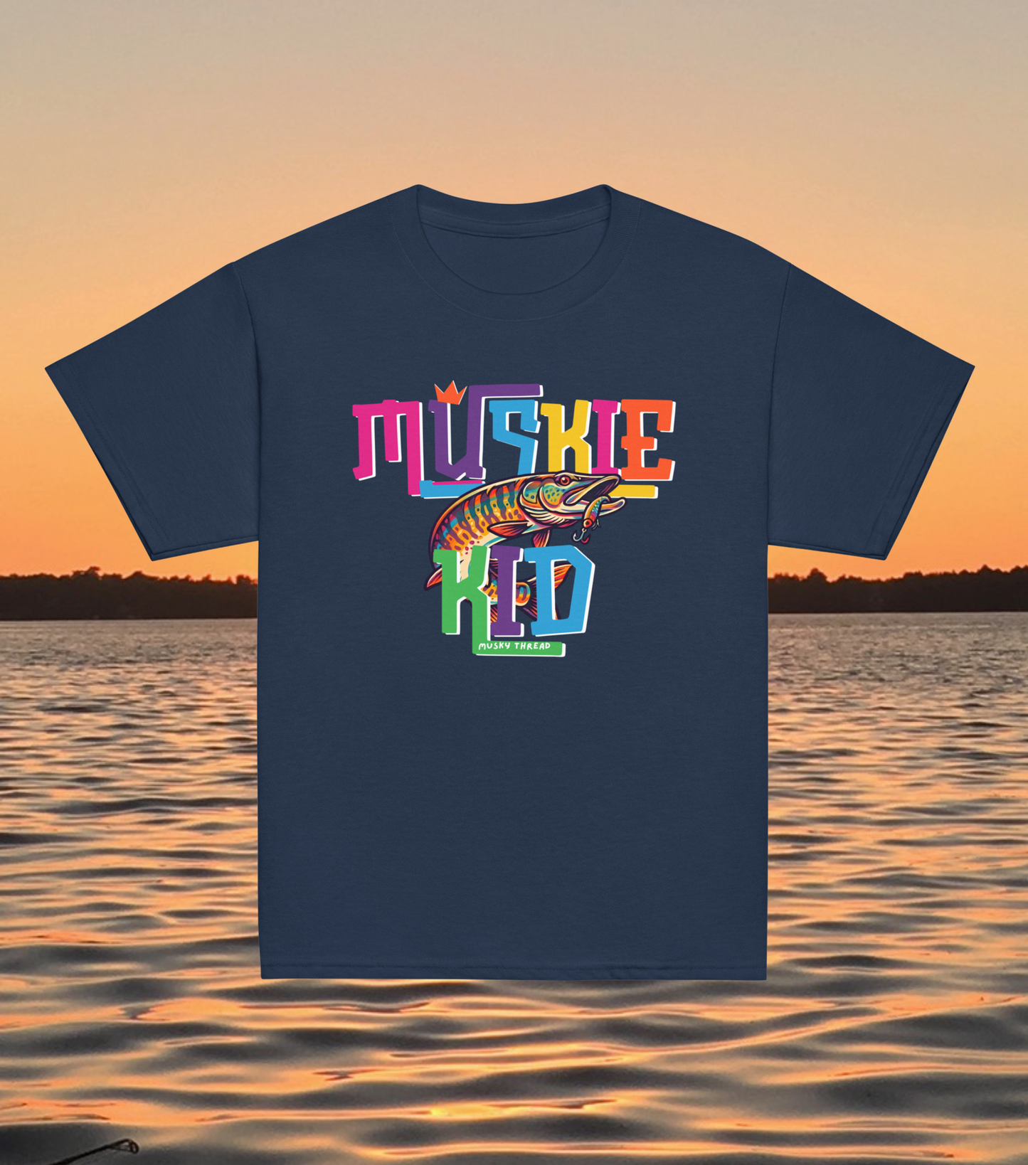 street-style youth graphic t-shirt with colorful hand-lettered Muskie Kid design featuring an illustrated musky fish and crown, displayed against a lake sunset background