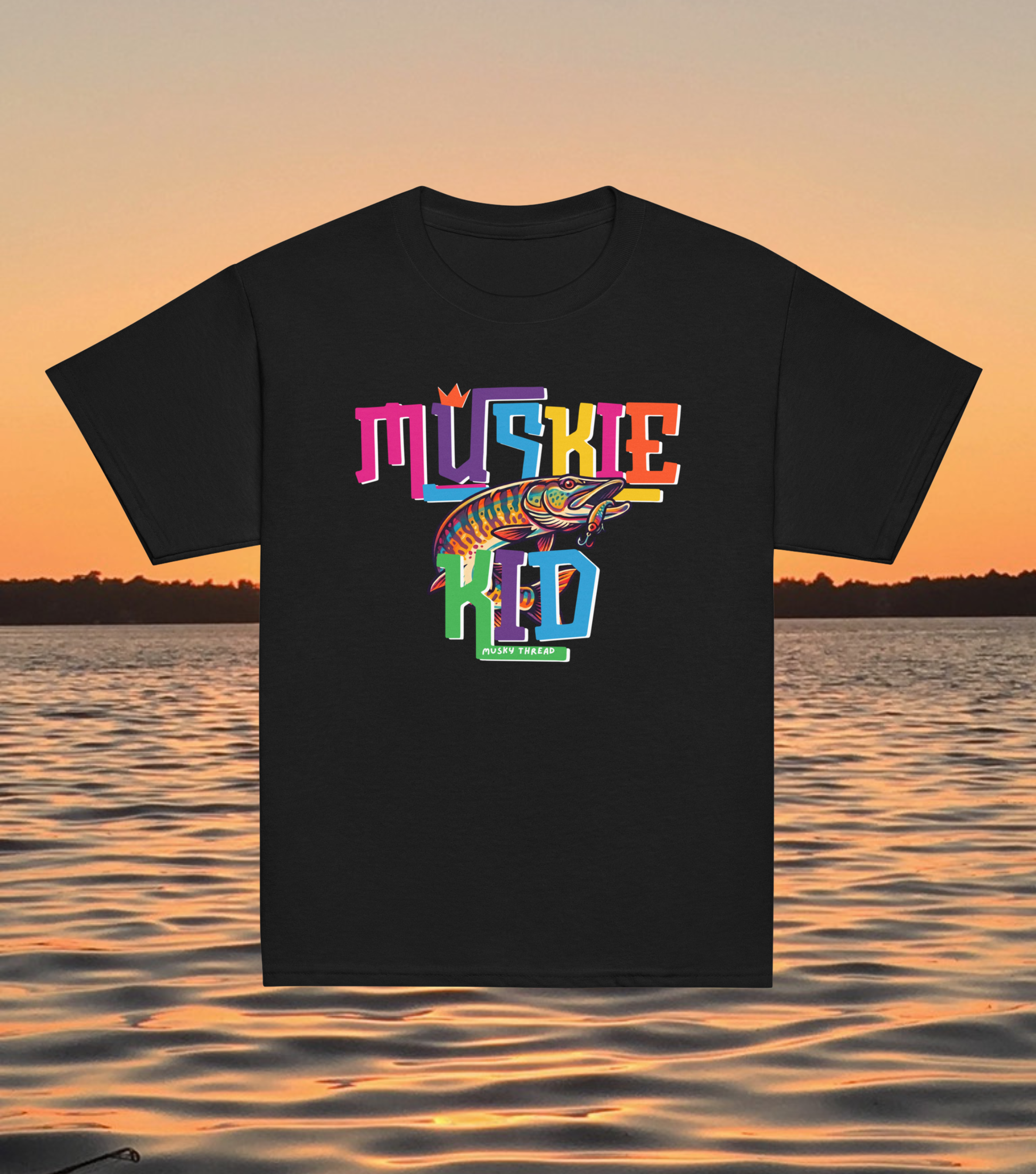 street-style youth graphic t-shirt with colorful hand-lettered Muskie Kid design featuring an illustrated musky fish and crown, displayed against a lake sunset background