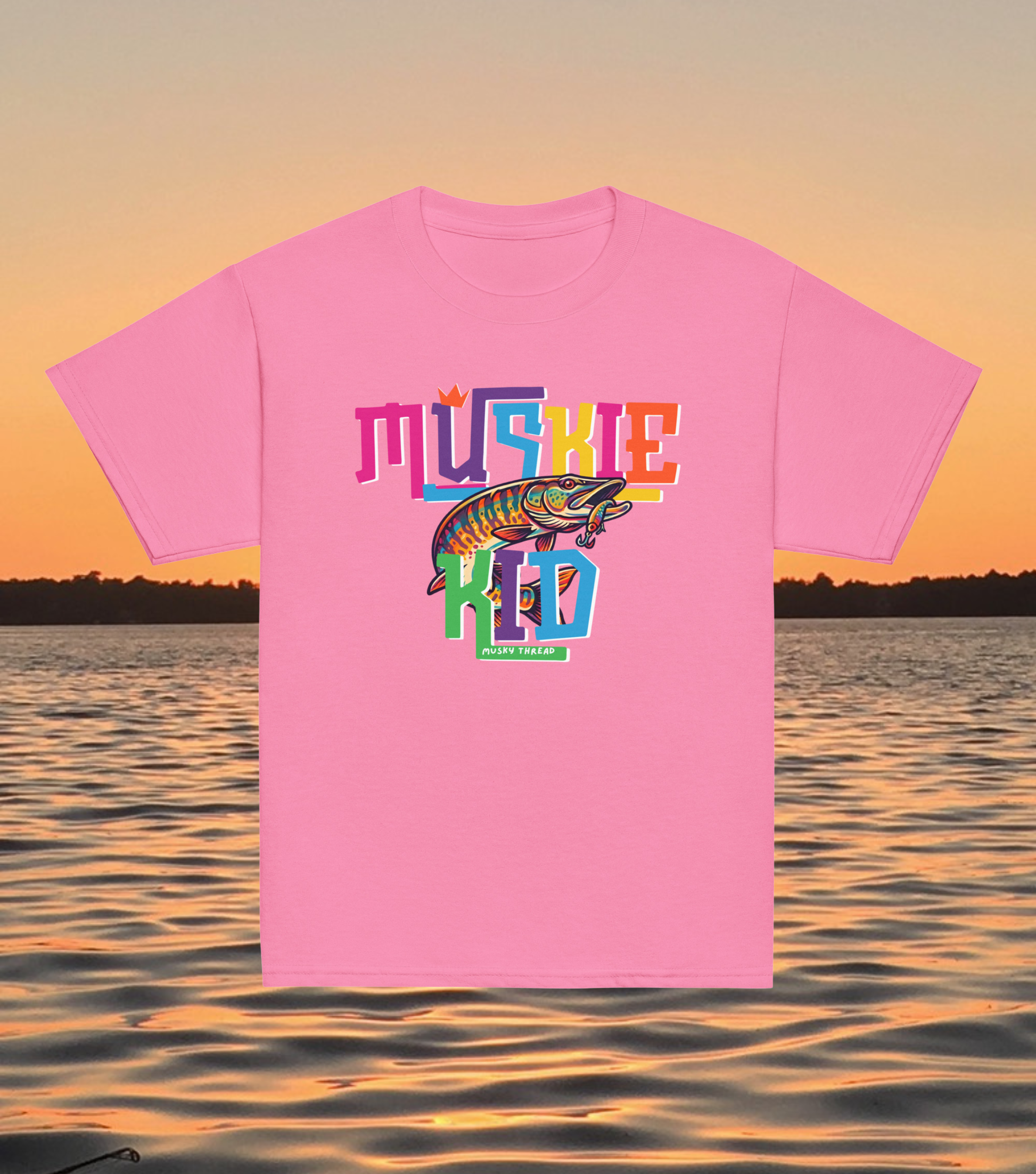 street-style youth graphic t-shirt with colorful hand-lettered Muskie Kid design featuring an illustrated musky fish and crown, displayed against a lake sunset background