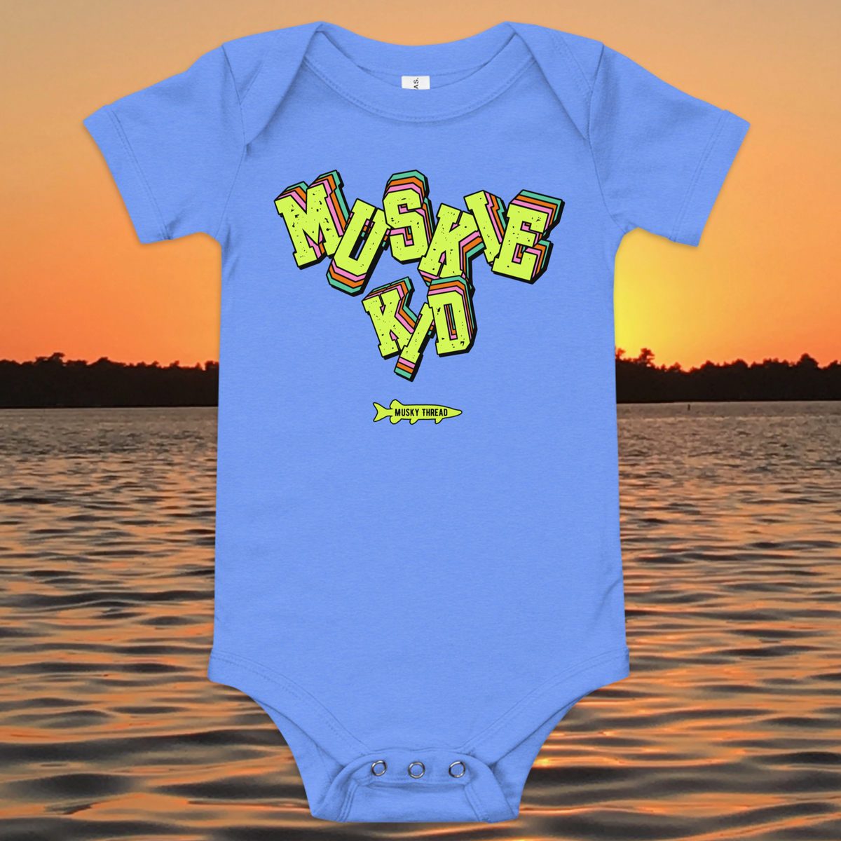 baby one-piece with neon green, pink, and teal "Muskie Kid" retro graphic and Musky Thread fish logo, shown against a lake sunset background