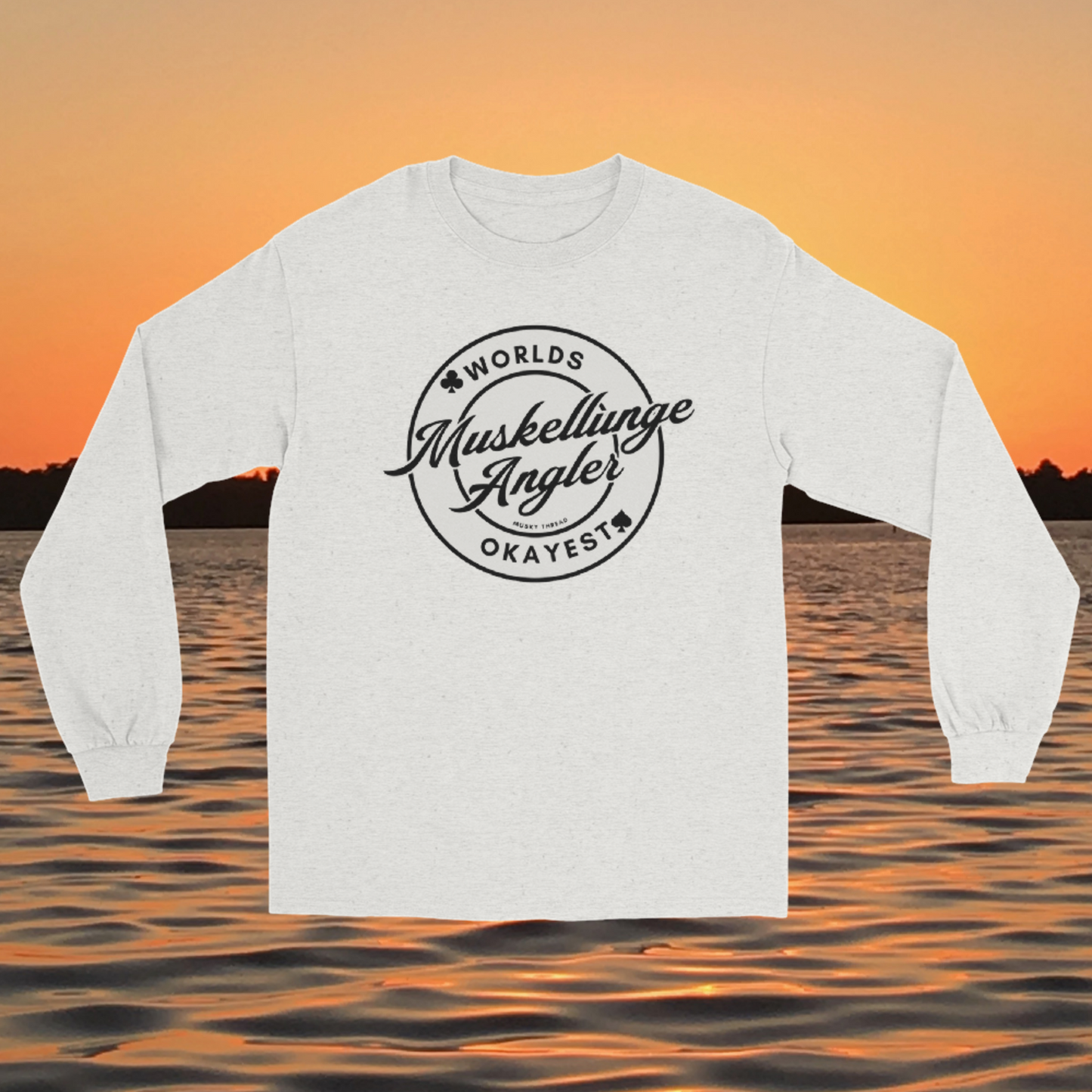 Unisex long sleeve shirt with Worlds Okayest Muskellunge Angler circular badge design, worn against a lake sunset background
